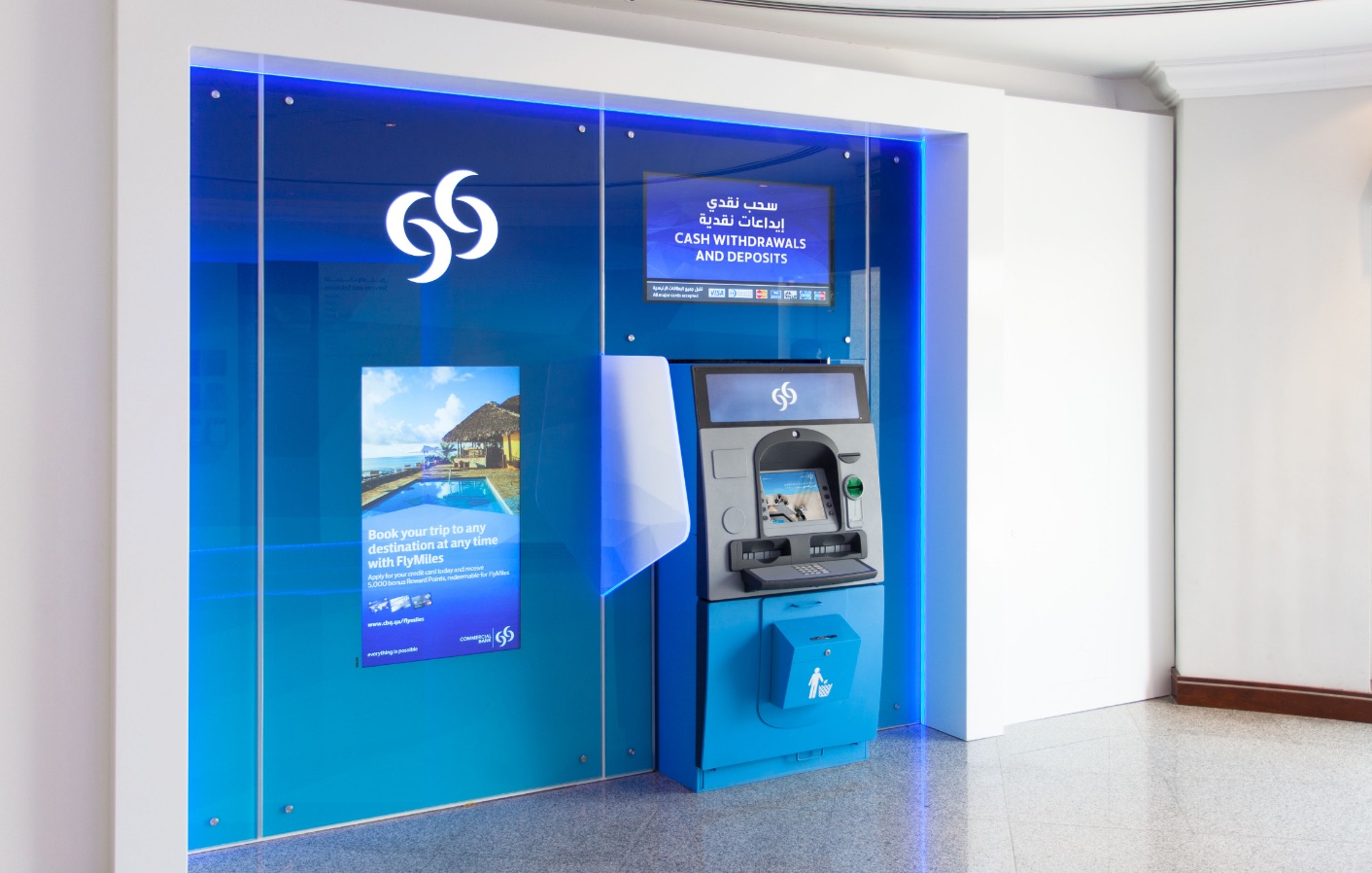 Commercial Bank ATM lobby with a backlit blue brand wall and a FlyMiles travel offer on screen